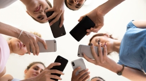 Diverse,Young,Women,Standing,Together,In,Circle,Holding,Smartphones,Looking